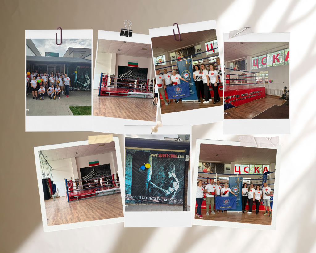 Group of people in white shirts posing outside a boxing gym with balloons and banners in the background.