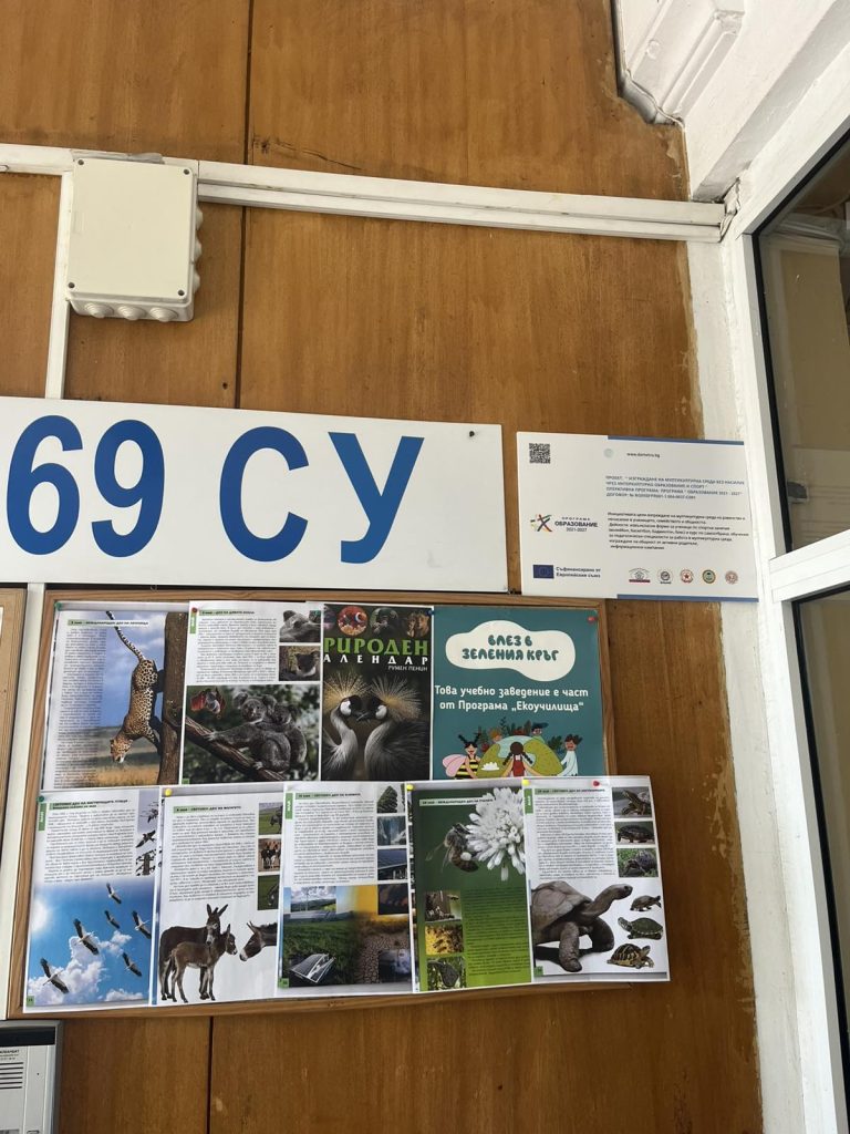 Wooden-walled display area with a bulletin board, a large blue'69 CY' sign, and assorted animal posters and information sheets photographed indoors.