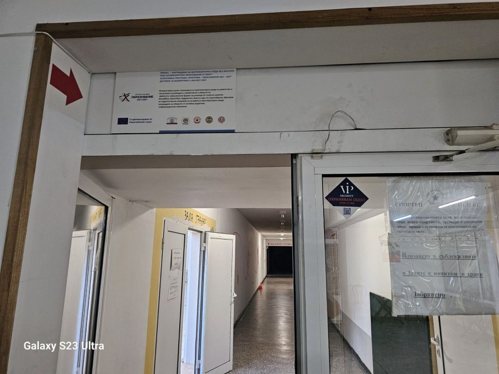 Interior corridor with white walls, several doors, and a large red arrow sign on the left wall.