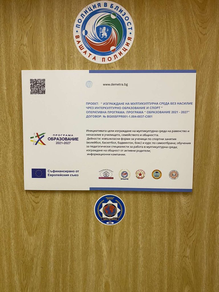 Information sheet about a multicultural education program on a wooden table, with several round logos above, below, and to the sides.